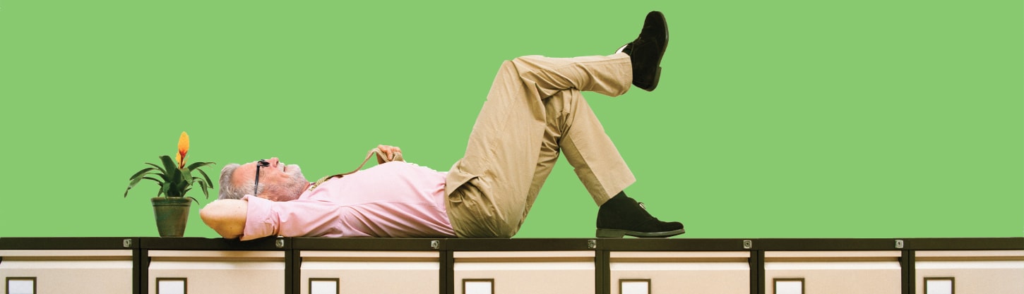 man lying next to a plant on top of a filing cabinet