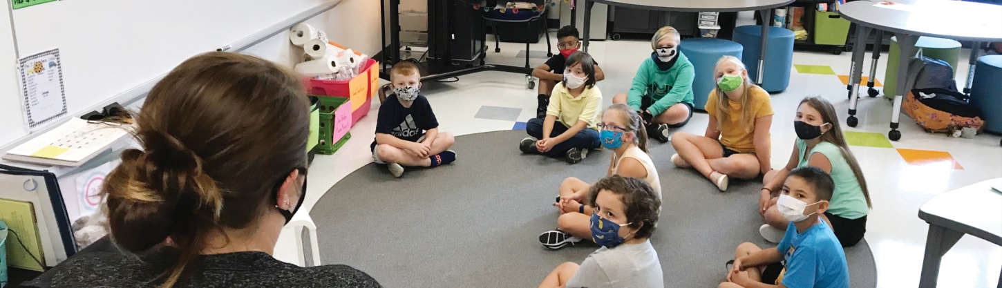 teacher speaking to a classroom of students wearing facial coverings