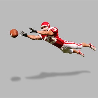 Football receiver is horizontal in the air, leaping to catch football